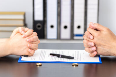 couple across from each other with wedding rings on table and a prenuptial agreement on the table