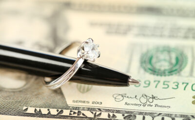 Wedding ring on pen, on money